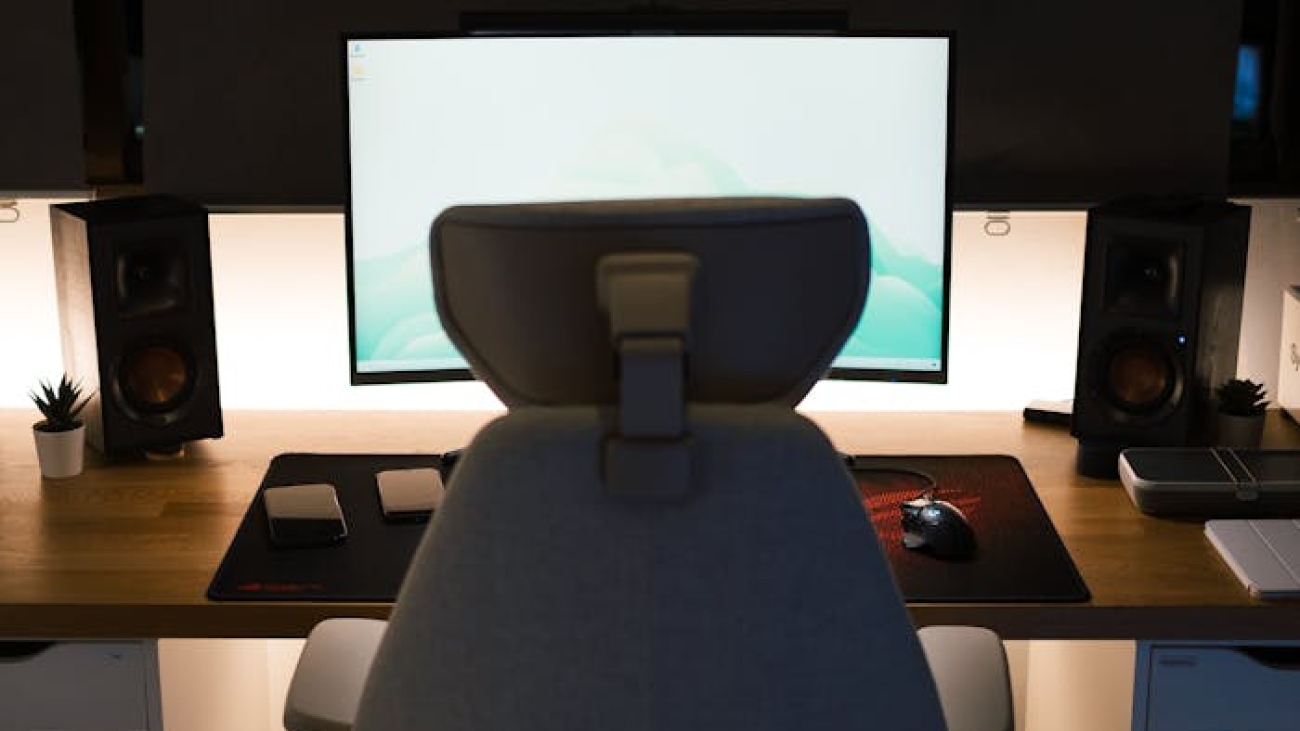 A stylish home office setup featuring an ergonomic chair, desk, and computer screen.