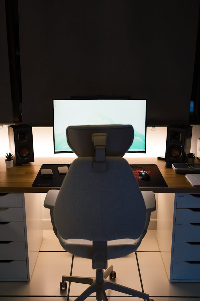 A stylish home office setup featuring an ergonomic chair, desk, and computer screen.