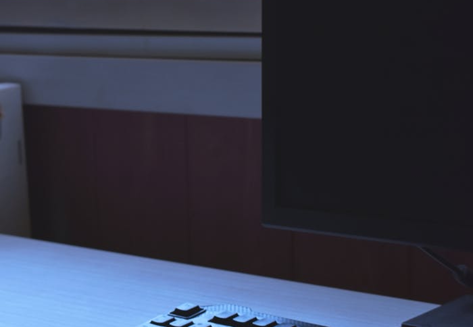 Minimalist workspace featuring a sleek keyboard and monitor by a window.