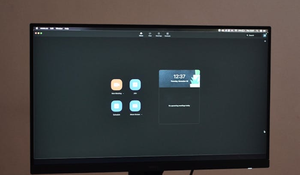 A sleek desktop setup featuring a monitor, keyboard, and mouse on a patterned tablecloth.