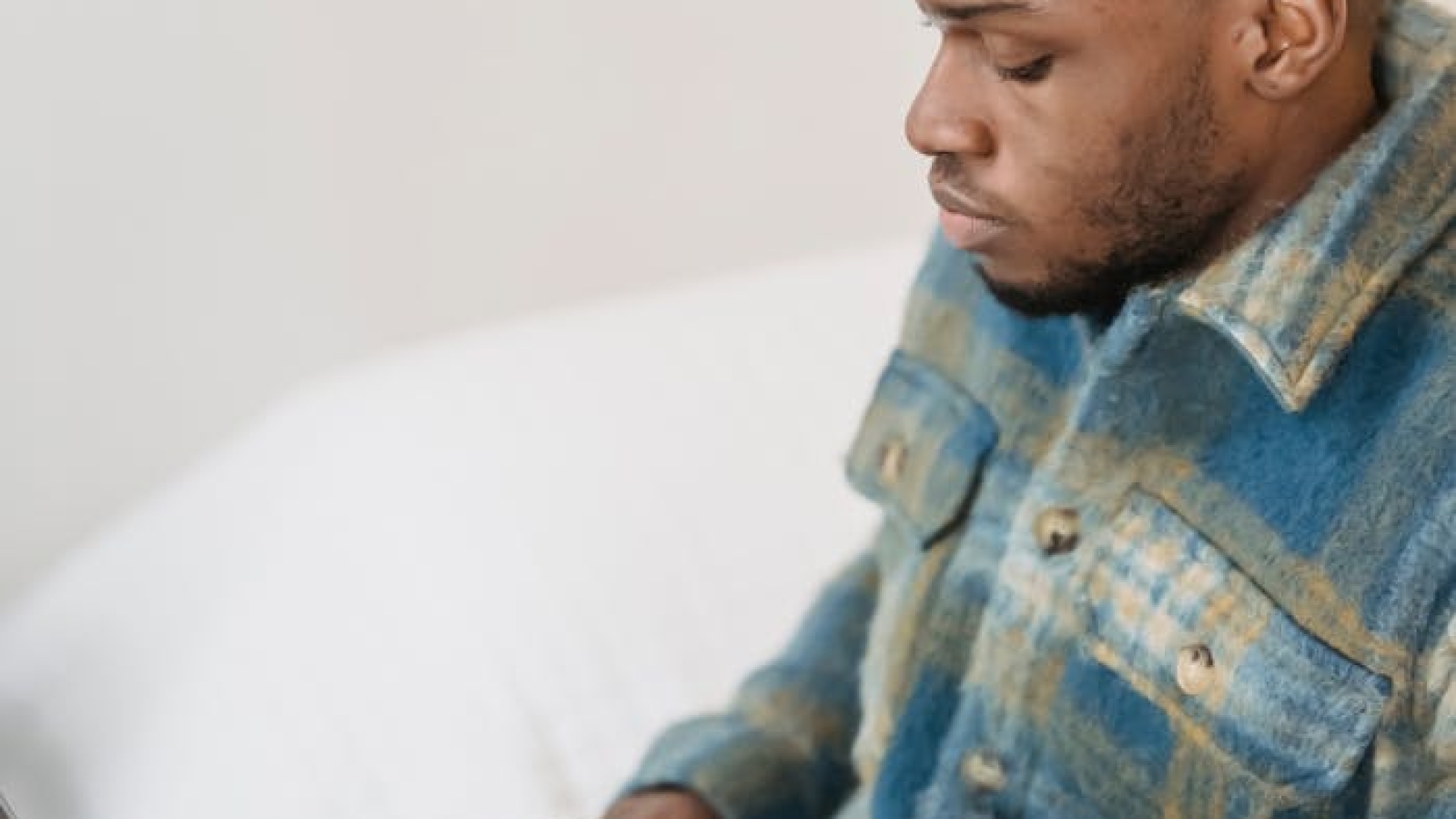 A young man deeply focused while working on a laptop from his comfortable living room.