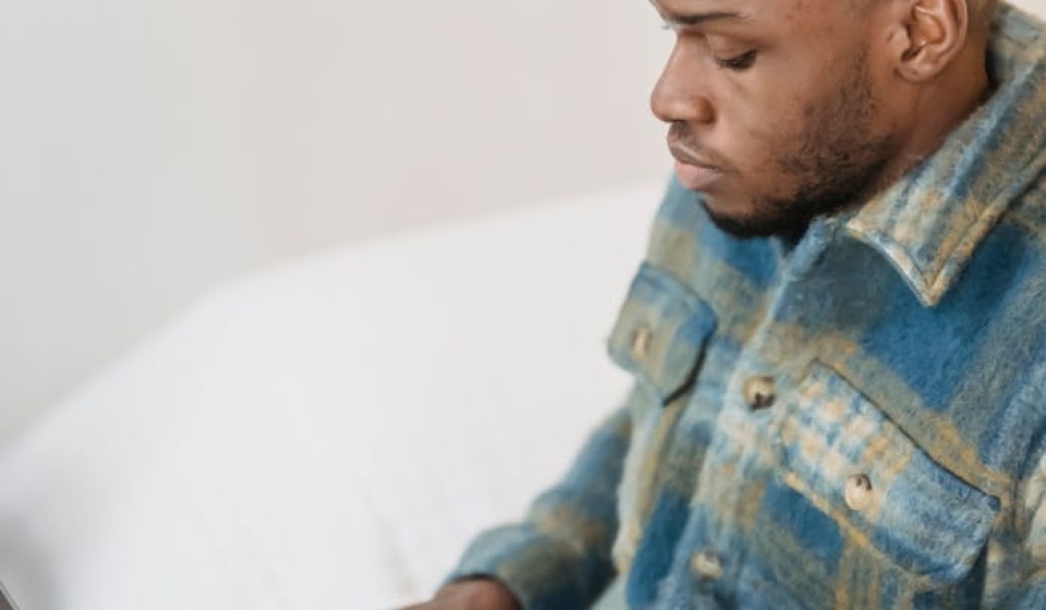 A young man deeply focused while working on a laptop from his comfortable living room.