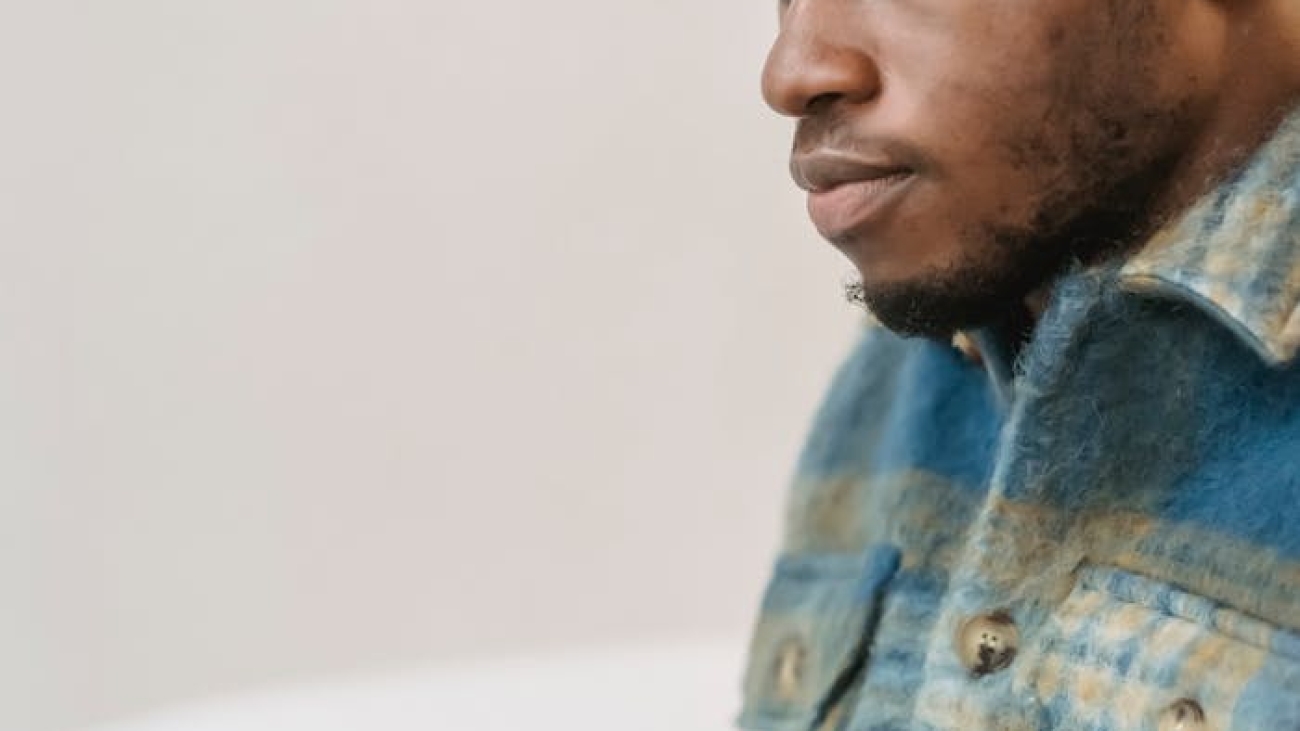 Young man in casual attire focusing intently while working on a laptop indoors.