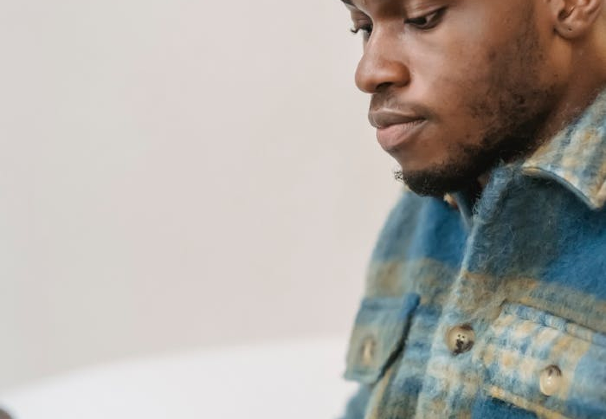 Young man in casual attire focusing intently while working on a laptop indoors.