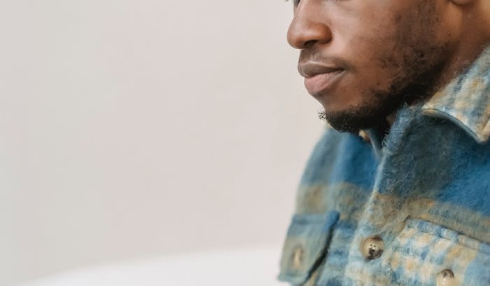 Young man in casual attire focusing intently while working on a laptop indoors.