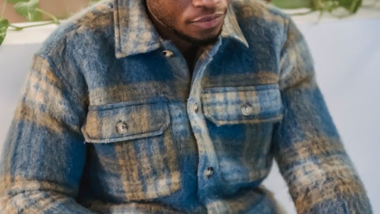 Young man in a casual setting intensely focused on his laptop, indoors.